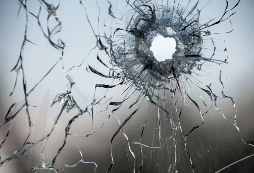 bullet hole in window glass with cracks abstract background close war