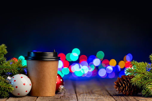 Coffee cup, Christmas tree branch with decor and garland bokeh
