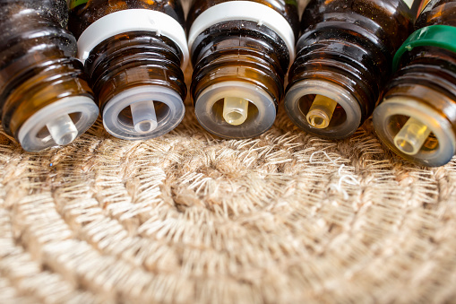 5 essential oil dropper bottles spilling in a line up on a jute rope circular placemat, soft focus macro