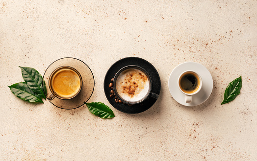Cups of assorted coffee on light background. Top view. Cafe and bar, barista art concept