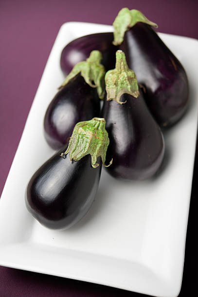 five eggplant on a white plate stock photo