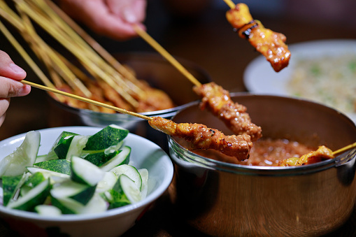 Chicken satay is a popular Malaysian street food dish consisting of tender marinated chicken skewers, accompanied by a flavorful peanut sauce and slices of cucumber.
