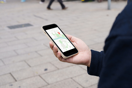 Woman with baggage in downtown city street searching location in map application online on smart phone using GPS navigating