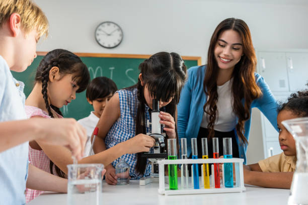 Adorable student learn with teacher in classroom at elementary school. Young brilliant and smart children sit on table and study chemistry experiment with happiness and fun activity at kindergarten. adorable estudiante aprende con maestro en el aula en la escuela primaria. los niños pequeños brillantes e inteligentes se sientan en la mesa y estudian química experimentando con felicidad y actividad divertida en el jardín de infantes.