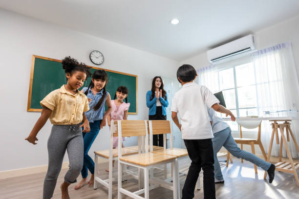 istock Group of student learn with teacher in classroom at elementary school. Attractive beautiful female instructor master support and look after children doing fun activity with happiness at kindergarten. 1503823349