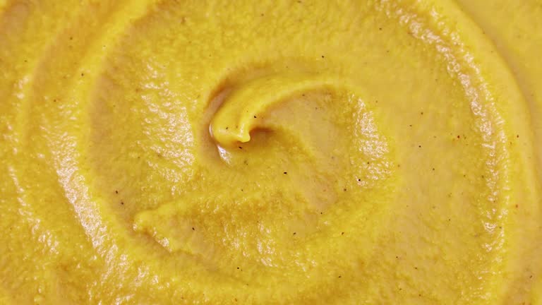 Bright yellow homemade mustard sauce circle rotation close up top view