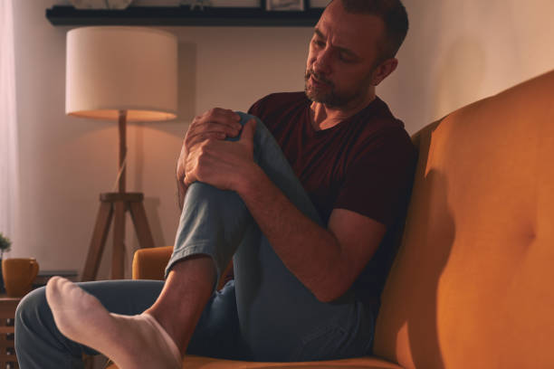 istock Man with knee pain sitting on a sofa at home. 1503854167