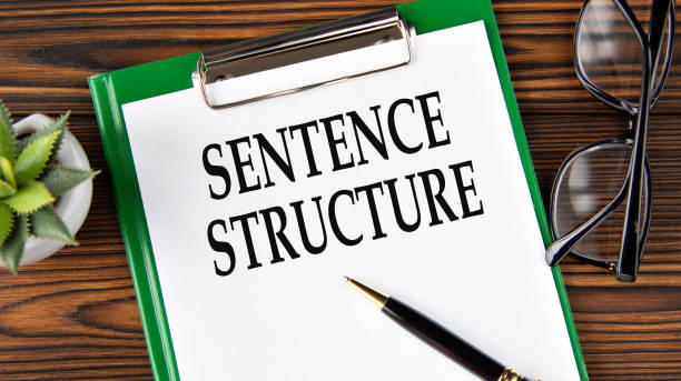 istock SENTENCE STRUCTURE - words on a white sheet on a brown wooden background with a pen and glasses 1503859537