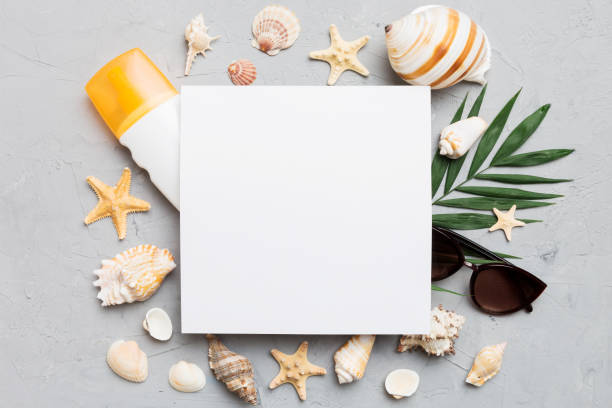 istock Summer time concept with blank greeting card and blank white paper on colored background. Seashells from ocean shore in the shape of frame separated with space for text top view 1503866995