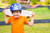 happy schoolboy in a protective helmet holds a skateboard