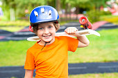 happy schoolboy in a protective helmet holds a skateboard