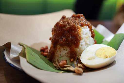 Nasi lemak is a fragrant Malay rice dish cooked in coconut milk and pandan leaf, toppings with fried anchovies, roasted peanuts and hard boiled egg, traditionally served on a banana leaf.