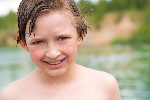 portrait of a little boy with wet hair after swimming in the lake
