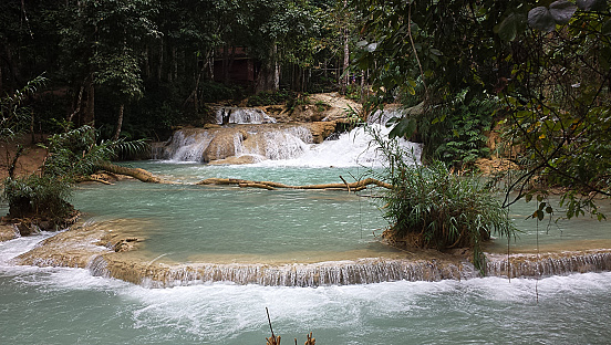 Turquoise waterfalls surrounded by dense tropical forest near Luang Prabang in Laos.