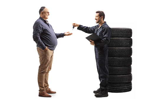 Machanic giving car keys to a mature man isolated on white background