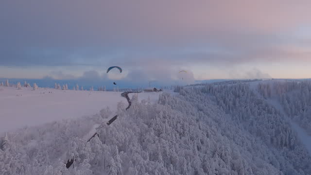 View of paraglider shot from the air, flying over winter landscape