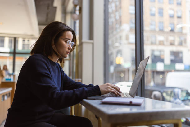 Learning in the Heart of Soho: Asian Female Student Engaged in Laptop Study Session stock photo