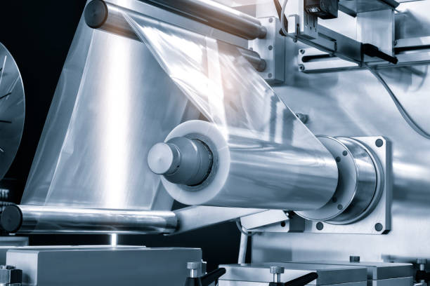 istock Automatic industrial machine for plastic packaging with light effect of products and food. shaft of an automated packaging line with plastic film in a light blue scene. product packaging concept 1503900664