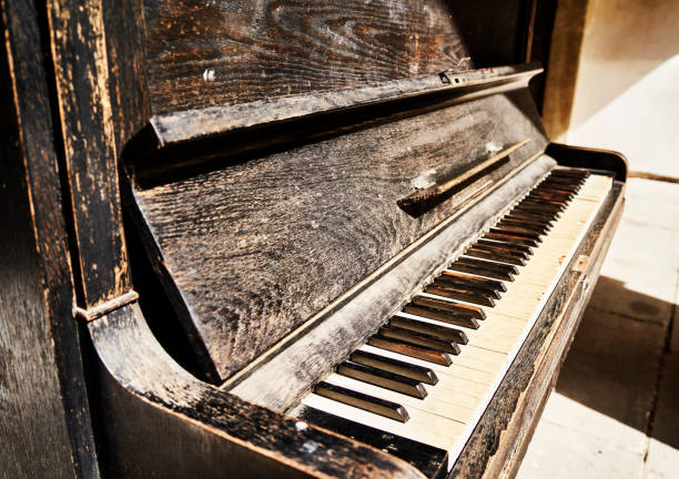 istock Old piano with weathered wood, peeling paint and worn keys 1503900950