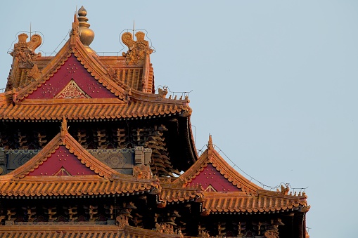 Close up of a grey roof section of one of the ancient palaces of the Forbidden City in Beijing China against the backdrop of a bright orange roof