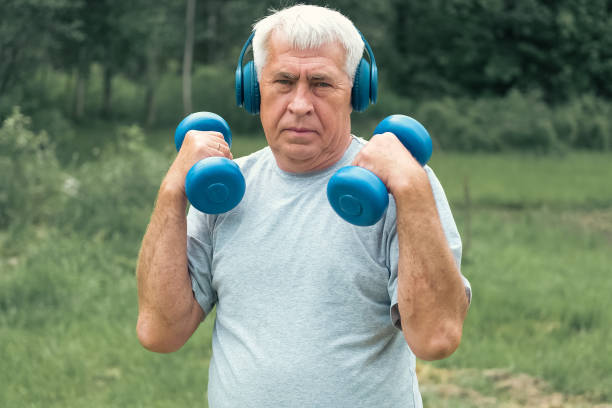 senior man working out outdoors. person lifting dumbbells. old male exercising at park. healthy people lifestyle. active sport training. older elderly sportsman doing fitness exercise. workout session - weight training weight bench weightlifting men imagens e fotografias de stock