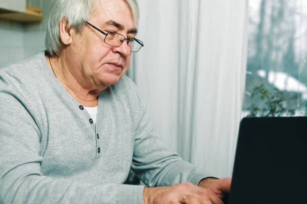 istock Senior man E-learning writing in notepad. Old male studying at home sitting at desk using laptop. Closeup hand writes in notebook with pen make note information. Older people distance learning concept 1503906865