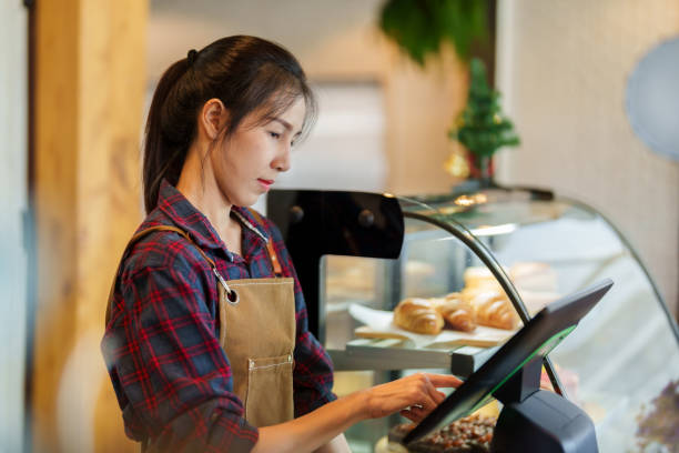 istock Close-up owner cafe bakery standing behind counter inside shop, close bakery, charging at store's cash register it's also machine that can accept orders in front counter, was focusing on that machine. 1503913545