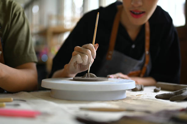 istock Young creative man focused on sculpting a raw clay on table in pottery workshop. Handicraft, creativity, hobby and activity concept. 1503914135