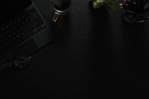 istock Dark modern workspace with laptop, notepad, coffee cup and glasses on black leather. 1503914152