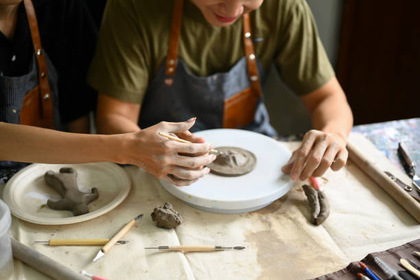 istock Ceramics art teacher helping student painting paint clay plate during lesson in workshop. 1503914706