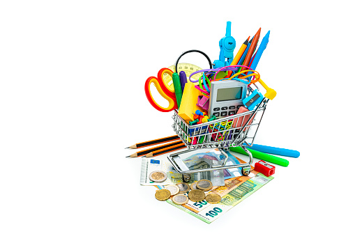 Shopping cart filled with multicolored school supplies shot on Euro banknotes isolated on white background. High resolution 42Mp studio digital capture taken with Sony A7rII and Sony FE 90mm f2.8 macro G OSS lens