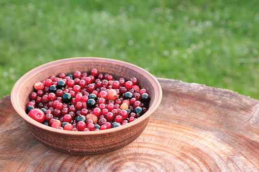 A plate of fresh various berries on a wooden background