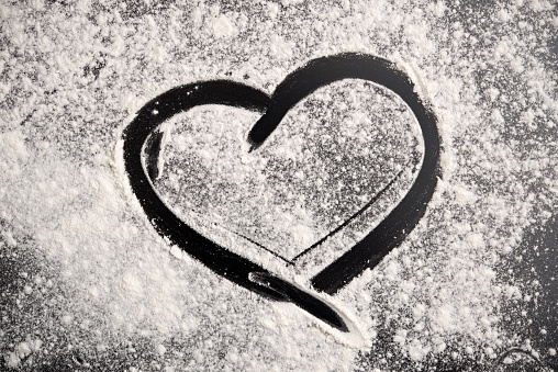 Heart shape and flour on black background