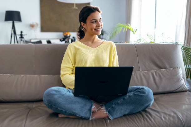 istock Beautiful young woman working with her laptop while sitting on a couch at home. 1503956465