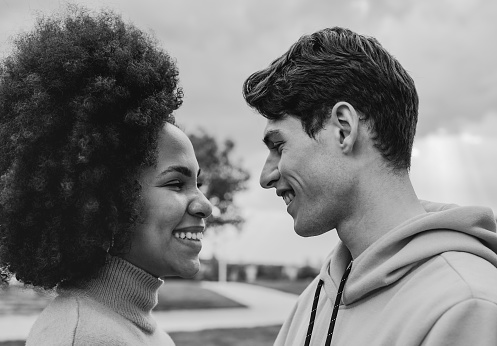 Happy multiracial couple having fun together outdoor - Black and white editing - Focus on the man face
