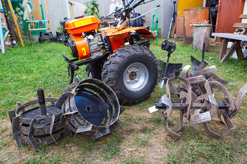 Agricultural walk-behind tractor with a set of attachments, hiller, milling cutters and lugs.