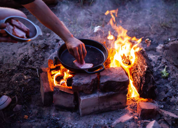 istock Frying bacon in a pan over a fire. Cooking outdoors in the evening. 1503993402