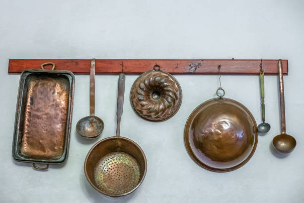 Vintage kitchen utensils hanging on wall in kitchen. Metal old kitchen appliances, baking molds, colander, ladles stock photo