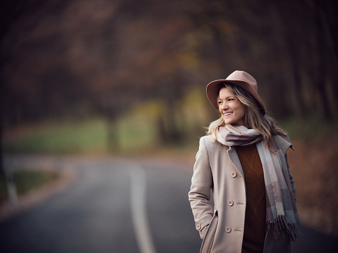 Happy woman enjoying in autumn day on the road in nature. Copy space. Photographed in medium format.