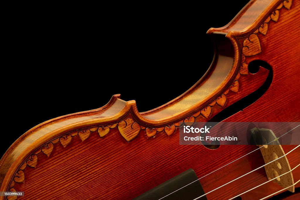 Violin on Black Violin on black background. Heart shapes are carved all around the edges of the soundboard (top deck) of the instrument. Black Background Stock Photo