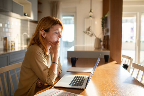 istock Young woman going over her finances at home while using her laptop 1504021975