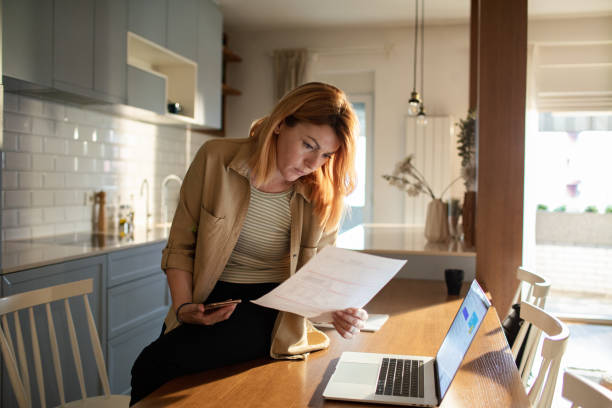 istock Young woman going over her finances at home while using her laptop 1504022757