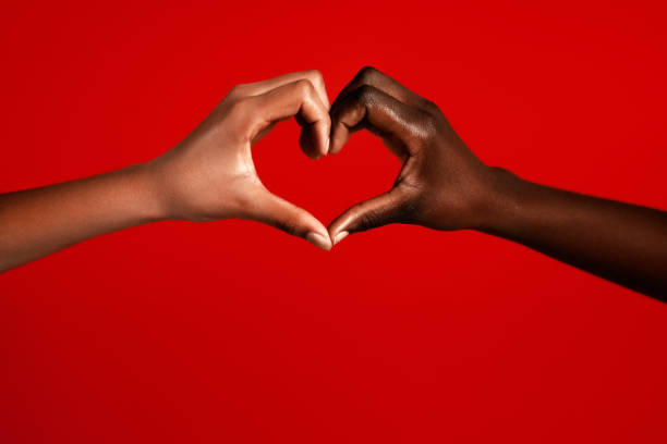 It's all about love Two multiracial girls making heart sign against red background heart hands multicultural women stock pictures, royalty-free photos & images