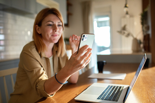 Close up of a mid adult woman using a smart phone at home