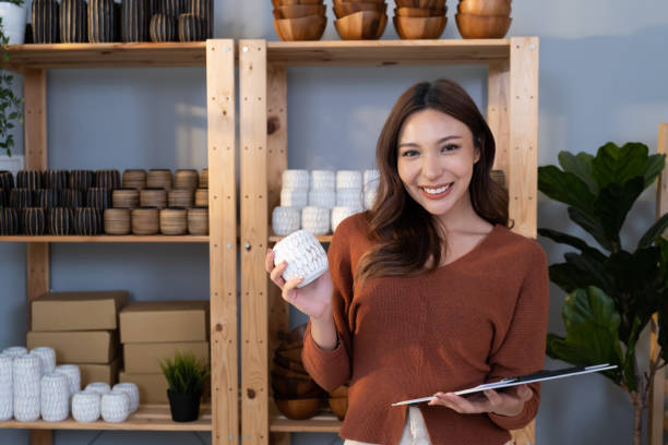 istock Young Asian female entrepreneur smile while talking on the phone and check customer order from online shopping inside of home office. New small business start up trend with online marketing. 1504039437