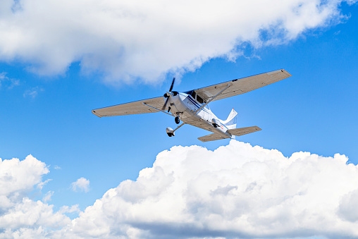 Single engine ultralight plane flying in the blue sky with white clouds