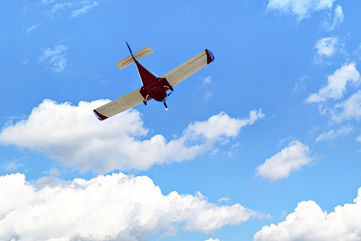 Single engine ultralight plane flying in the blue sky with white clouds