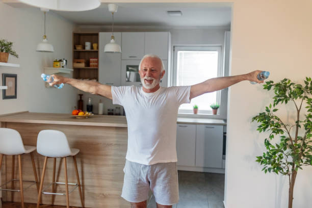 istock Senior man is exercising at home and using water bottles instead of weights. 1504040359