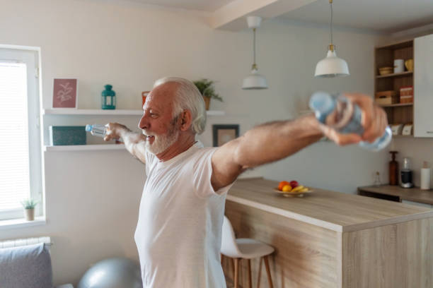 istock Senior man is exercising at home and using water bottles instead of weights. 1504040407