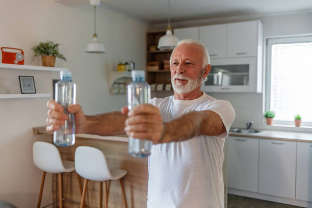 istock Elder man using bottle of water for home workout. 1504040594